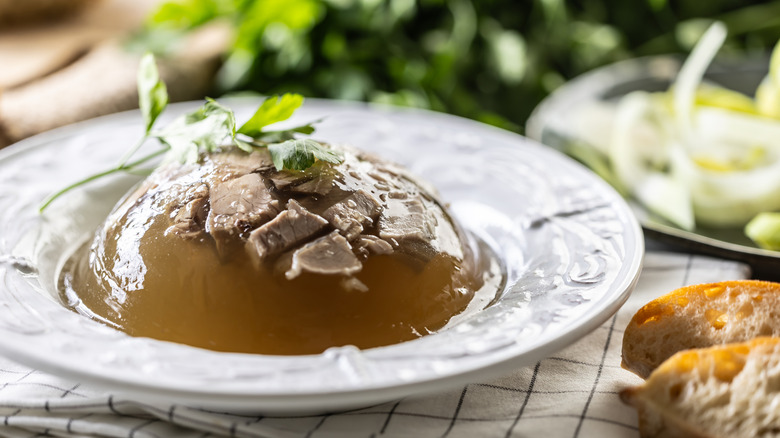 Bowl of beef aspic garnished with herbs