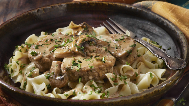 Beef stroganoff on a dark-colored plate with a fork