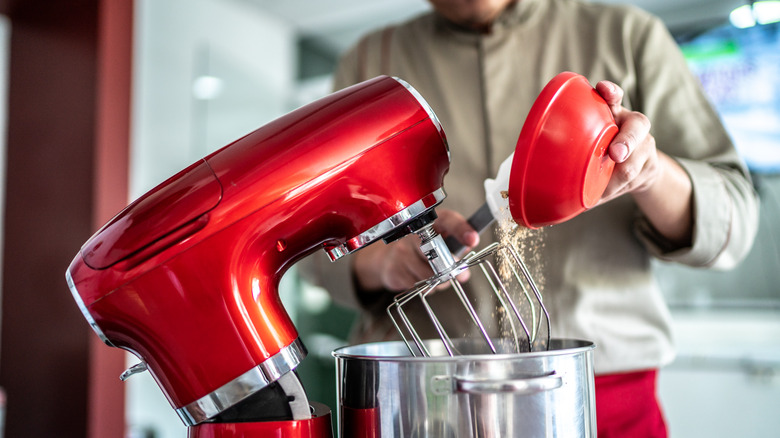man adding ingredients to a KitchenAid mixer