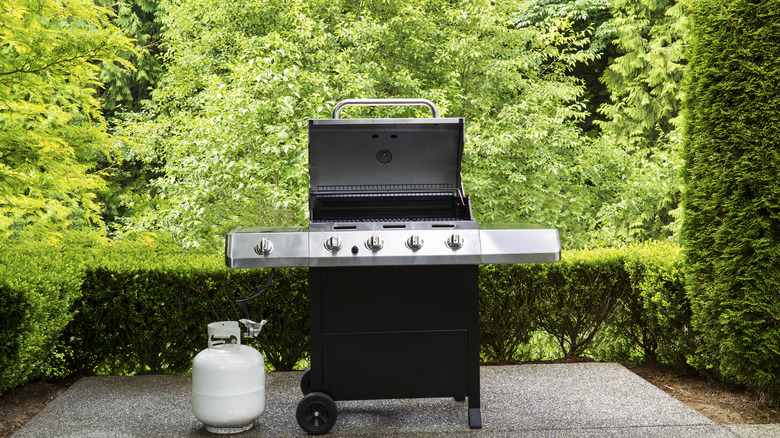 Grill with propane tank in back yard