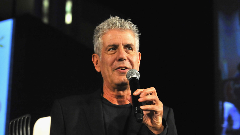 Anthony Bourdain speaks at an event while holding a microphone