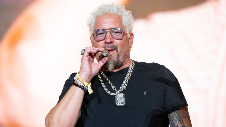 Chef Guy Fieri smokes a cigar at a public event