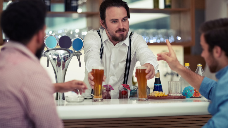 Bartender serving two guests beers