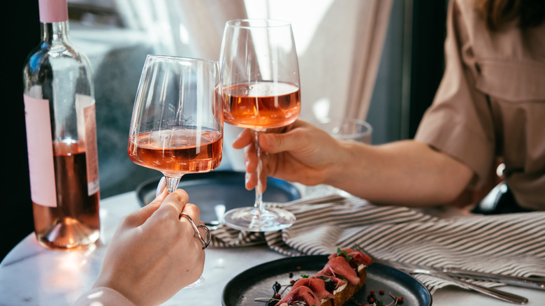 Hands clinking glasses of rosé in a restaurant