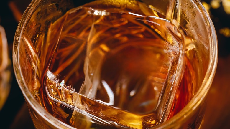 Close-up of scotch in glass with one large square cube