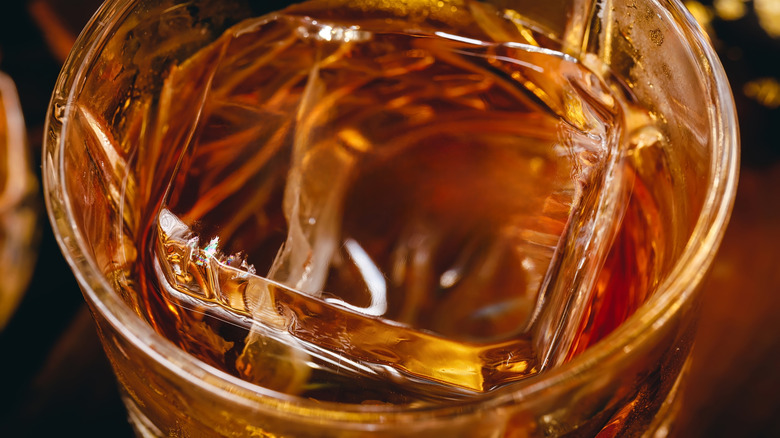 Close-up of scotch in glass with one large square cube