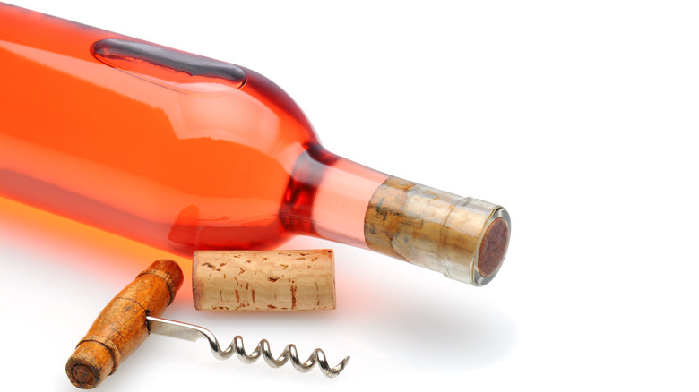 A bottle of White zinfandel lying on its side with a corkscrew