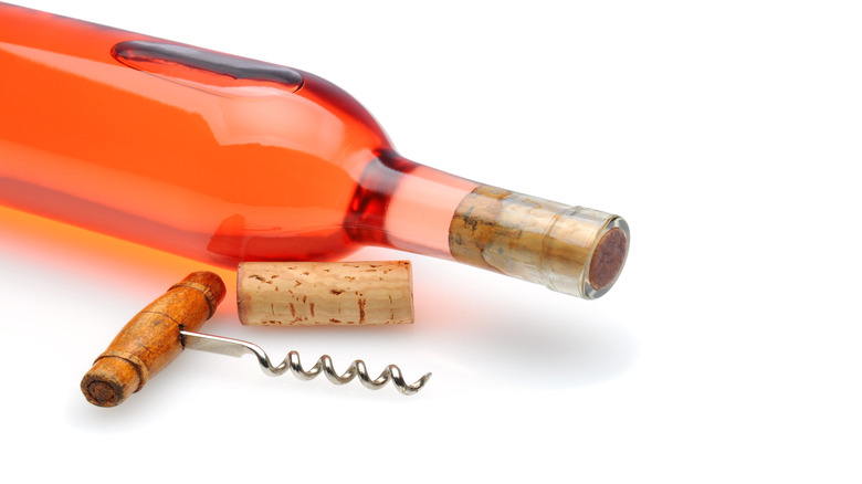 A bottle of White zinfandel lying on its side with a corkscrew