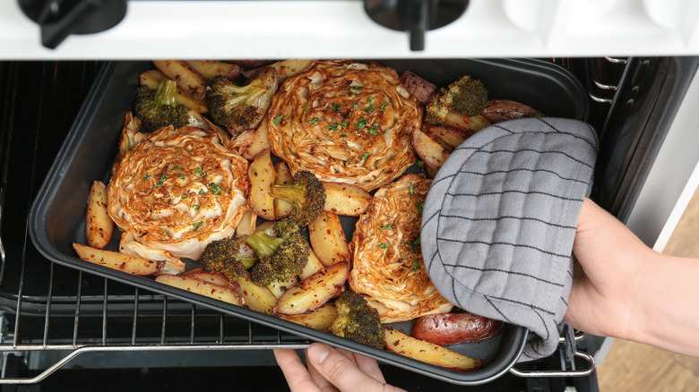 Someone takes cabbage steaks out of the oven.
