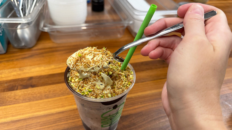 hand mixing Shake Shack Dubai Chocolate Pistachio Shake with spoon