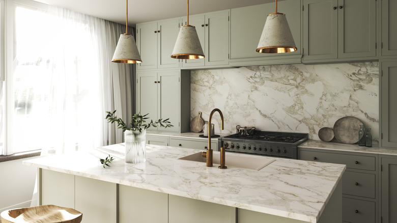 A kitchen with green cabinets and marble countertops
