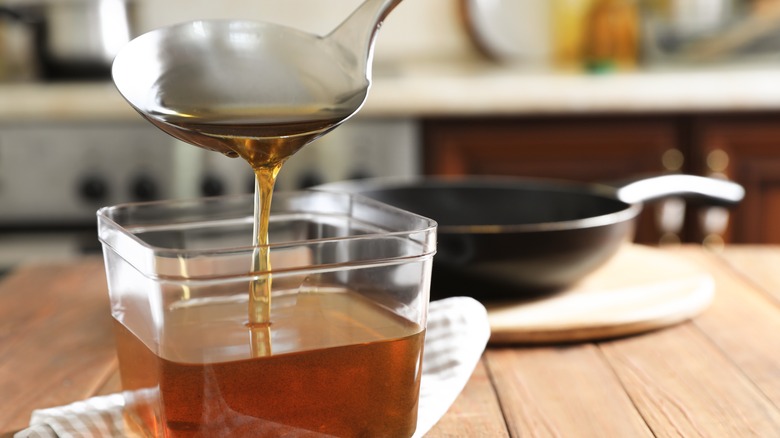 ladle putting cooking oil in container