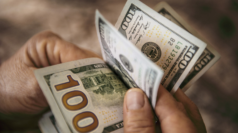 Hand flipping through a stack of $100 bills