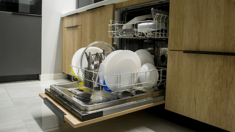 A panel-ready dishwasher door hangs open, revealing the dishes inside