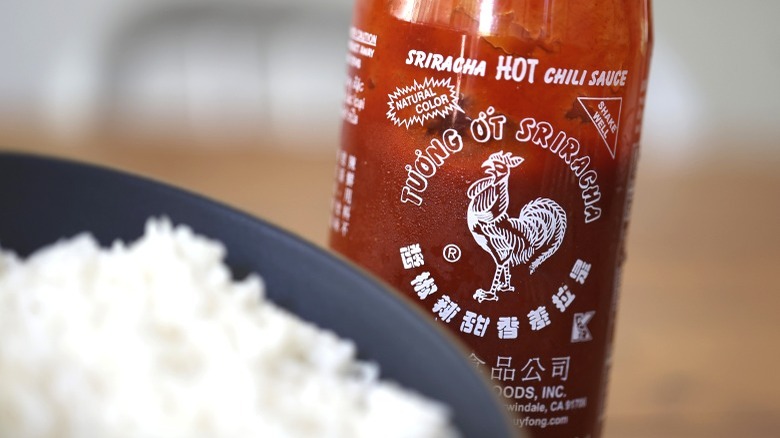 huy fong sriracha bottle next to bowl of rice