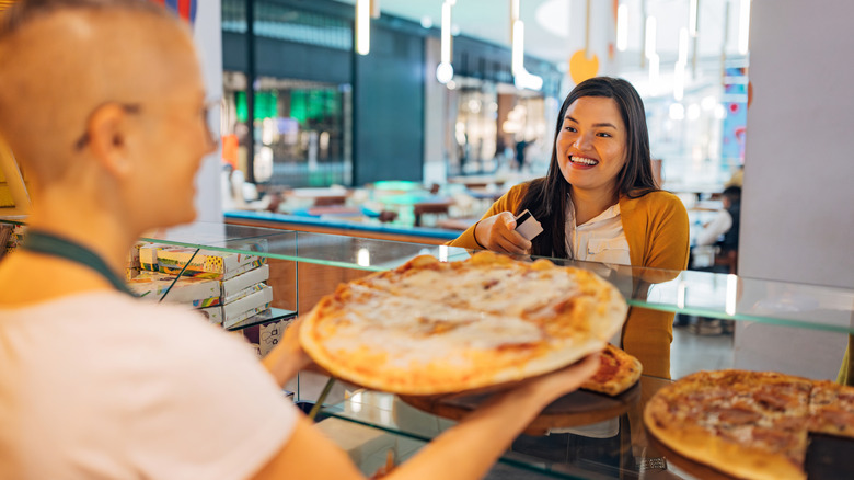 Pizza worker handing over pizza to customer