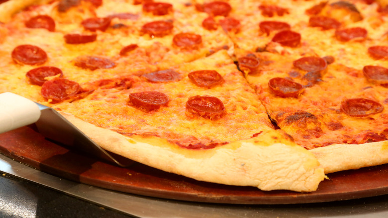 Basic slice of New York-style pepperoni pizza getting extracted from a pie