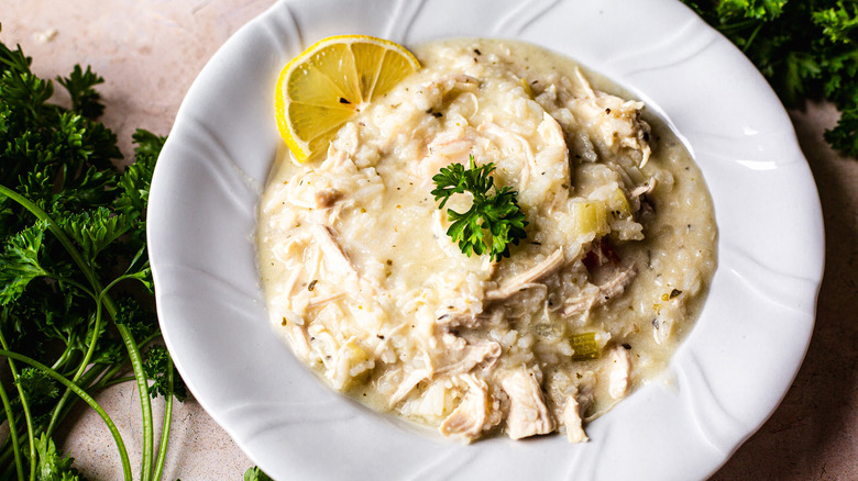 Avgolemono soup in bowl with parsley and lemon