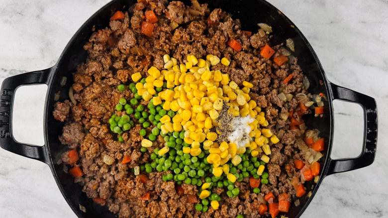Shepherd's pie filling with corn, peas, salt, and pepper on top