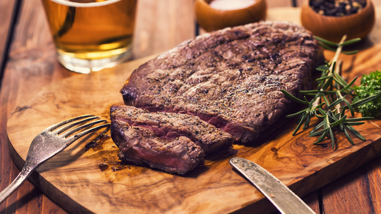Cooked steak on a wooden cutting board.