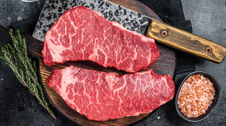 Raw Denver steaks on a board.