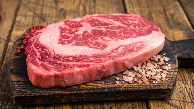 Raw ribeye on a board with salt.