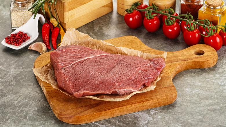 Raw beef shoulder on a board.