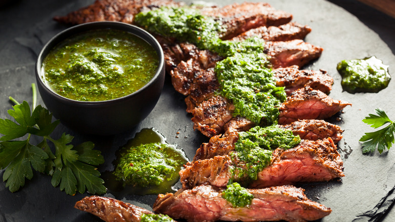 Cooked skirt steak topped with chimichurri.