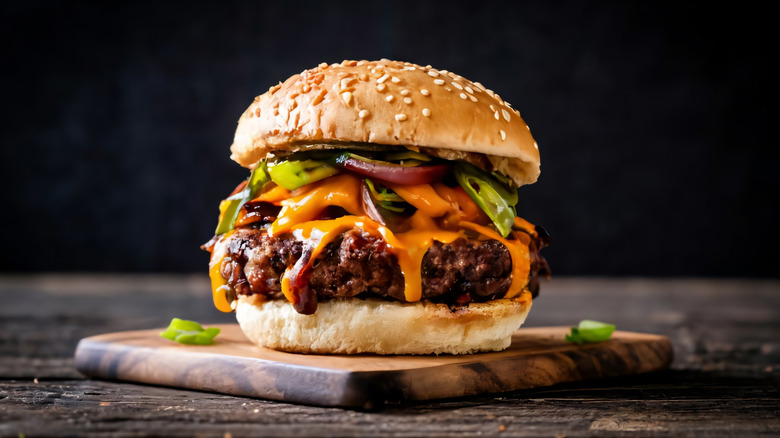 Cheeseburger with toppings on a wooden board