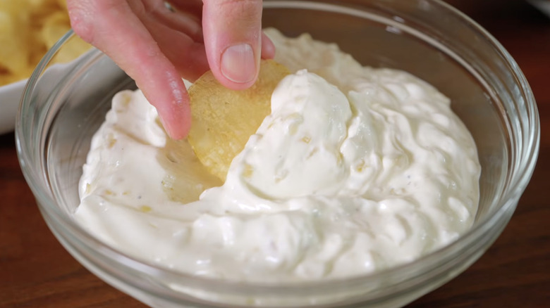 Dipping a chip into French onion dip.