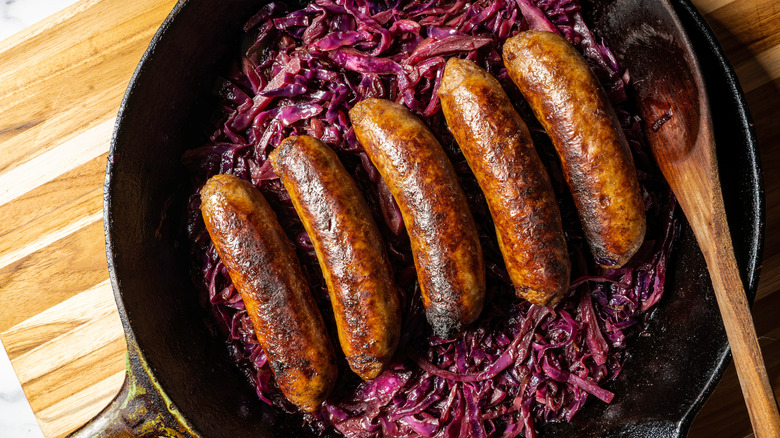 Skillet of beer-braised bratwurst with cabbage.