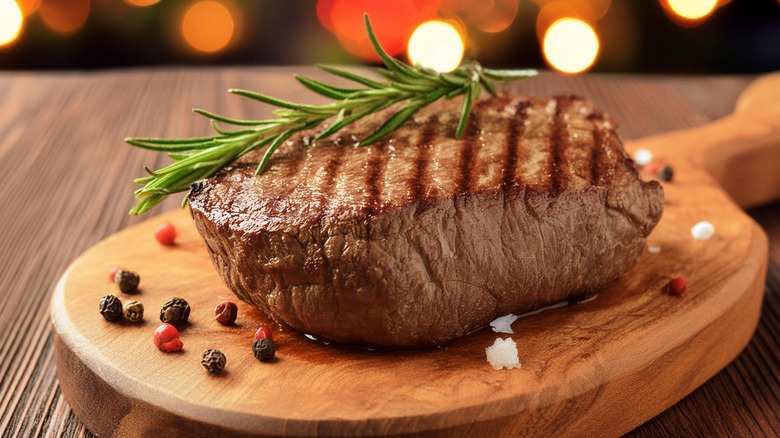 Steak resting on a wooden cutting board with herbs and seasonings