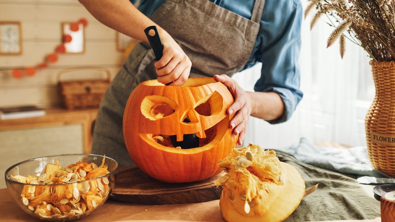 Woman carving orange pumpkin 