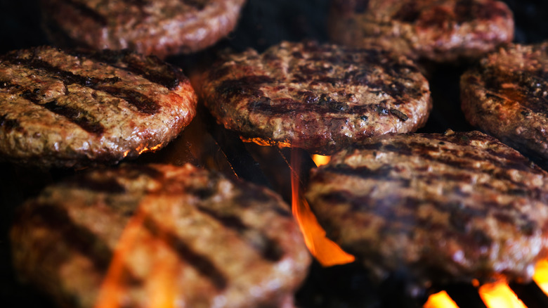 Burger patties being cooked on a flame grill