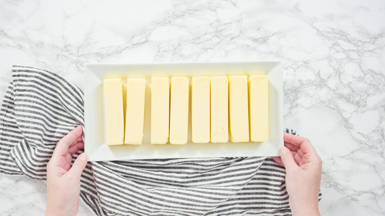 Hands holding platter of butter sticks