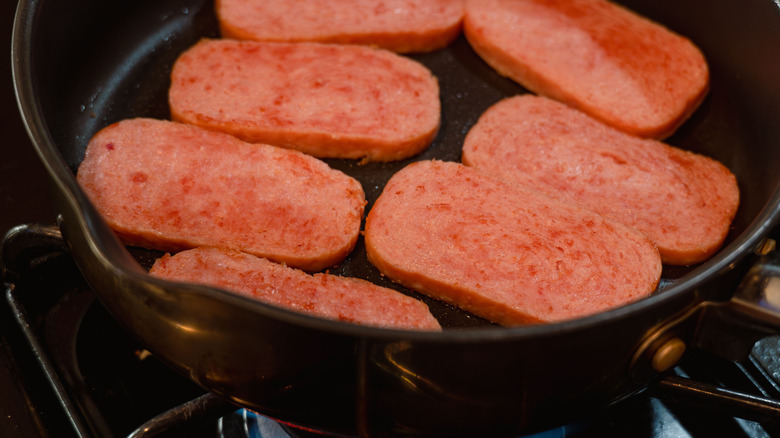 Spam frying in a cast iron pan.