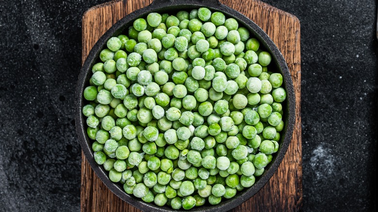 frozen peas in a cast iron pan on a wooden board