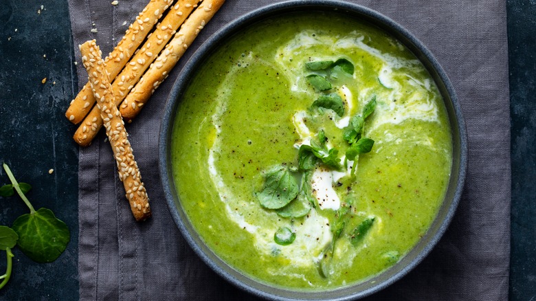 pea soup in a bowl next to sesame breadsticks
