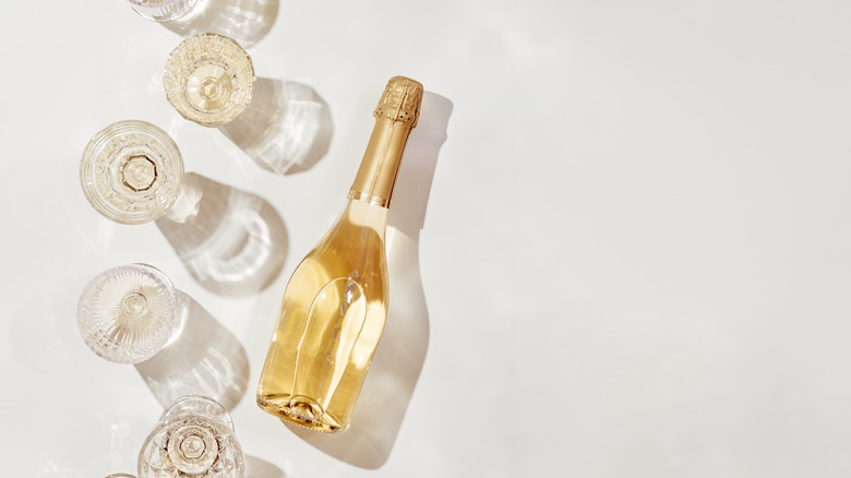 Bottle and glasses of white wine laying on white background