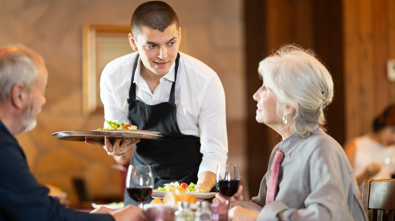 Waiter serving an older couple in a restaurant