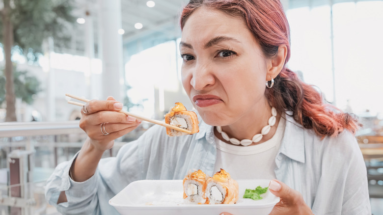 A woman smelling a piece of sushi