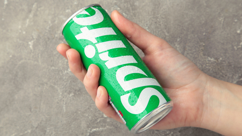 Someone holds a narrow can of Sprite.