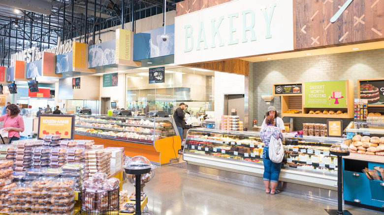 woman being helped at the bakery counter while others shop in the department