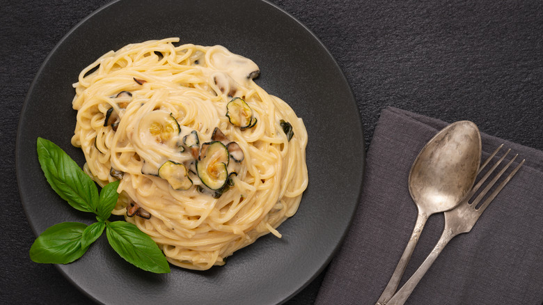 Spaghetti alla Nerano on a black plate with fork and spoon