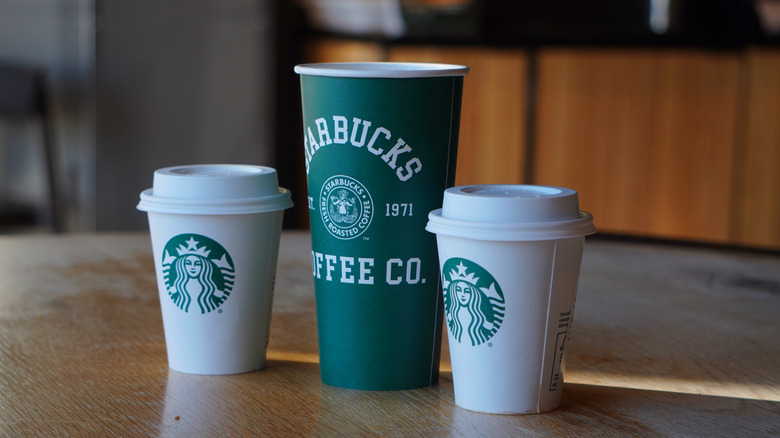 Side angle of Starbucks 1971 Roast in Short cup, special-edition green Venti cup, and Dark Roast Verona in Short cup