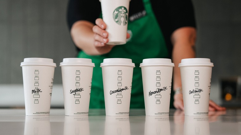 A line of Starbucks cups with various milk customizations written on sides