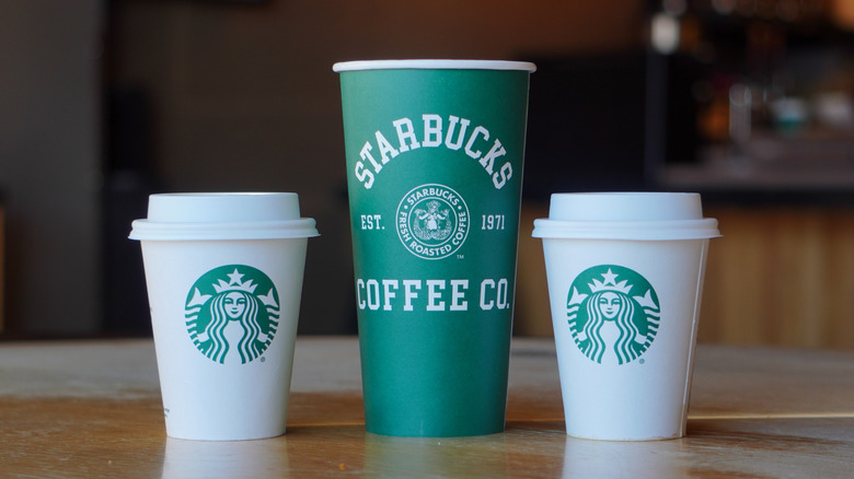 two short, white Starbucks cups and one tall green one