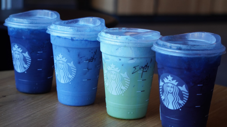 Side view of Starbucks' Starbucks' Blue Coconut Lemonade Refresher, Ocean Drink, Iced Blue Coconut Matcha, and Blue Coconut Refresher (left to right).