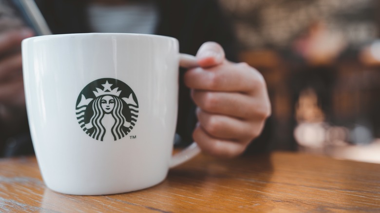 Hand holding Starbucks coffee mug