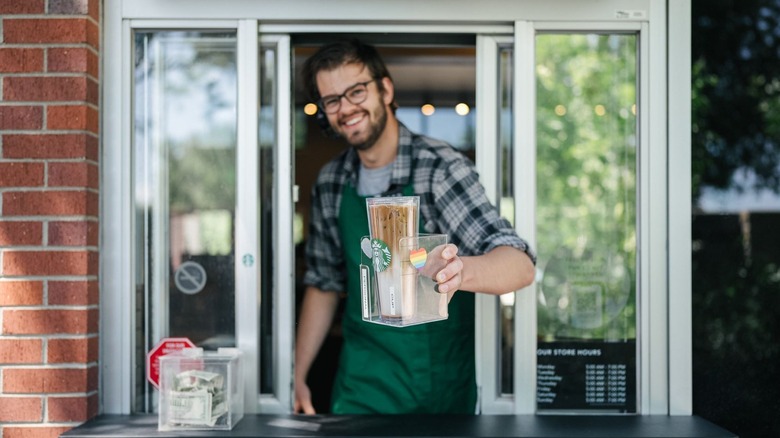 Starbucks barista passing a tumbler through the drive thru